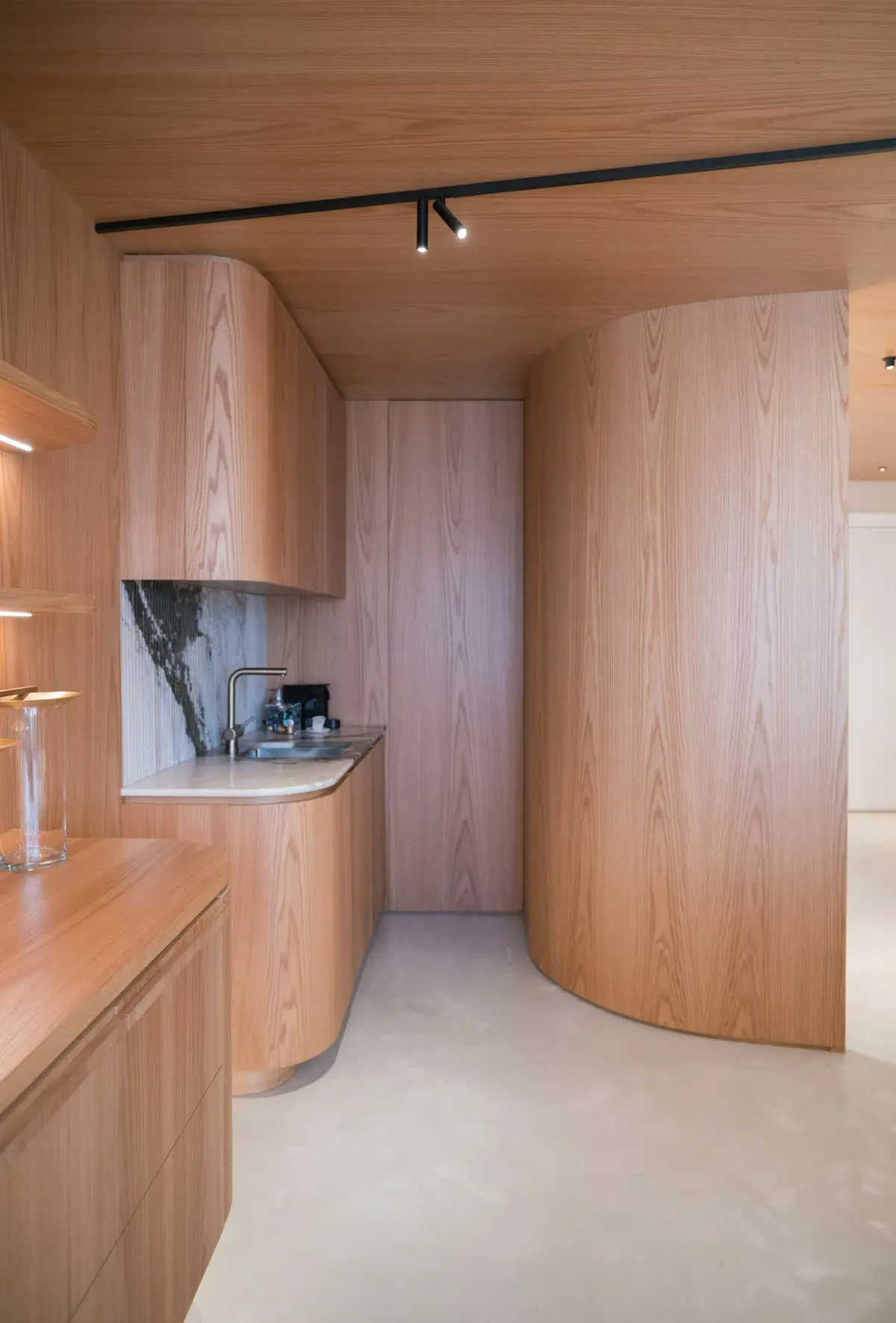 Luxury apartment kitchen with curved timber joinery and marble benchtop